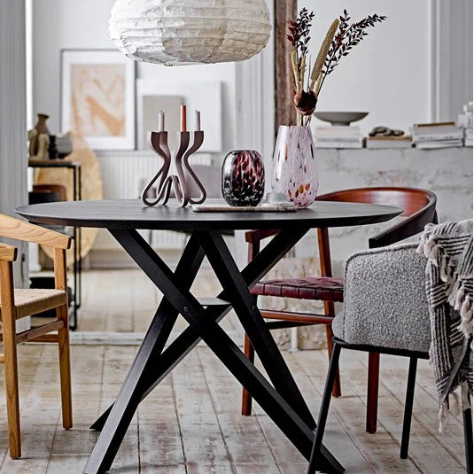 Dinning room table with many vases and candle sticks.