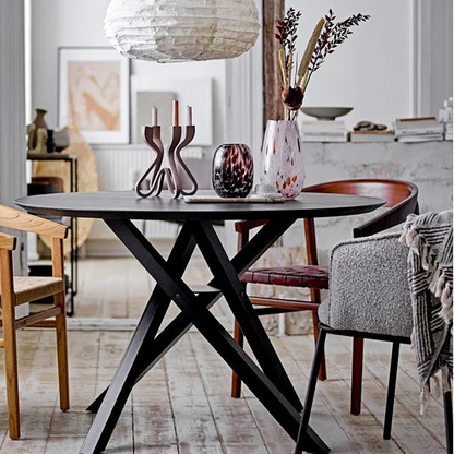 Dinning room table with many vases and candle sticks.